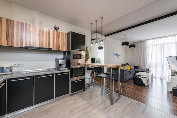 a living room with couch, chairs, and tablesNice apartment interior showing off the kitchen and living room with a big window in the background